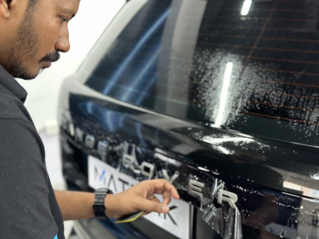 Mann der eine PPF-Folie an einem Auto verklebt, Auf dem Nummernschild steht die Firma Matmak.