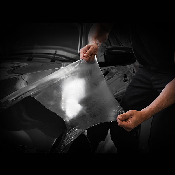 Steinschlagschutzfolie ORAGUARD 2815+ wird auf einem schwarzen Auto verklebt.