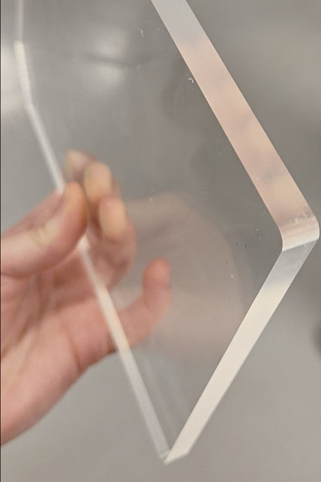 Mit dem Flachbett-Schneideplotter F-Serie Vantage gefrästes Acrylglas. Die Kante glänzt in matter Optik. Eine ca. A5 große Platte wird in einer Hand gehalten.