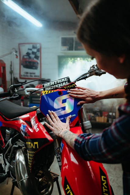 Die Holo Silver THSX-110 wurde bedruckt und wird von einer Frau auf ein Motorrad in einer Werkstatt geklebt. 